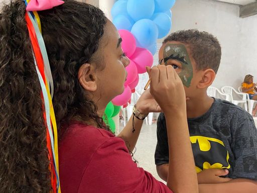 Voluntária fazendo pintura no rosto de uma criança