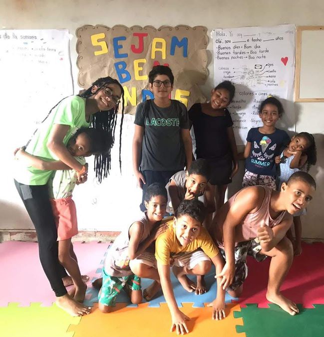 Voluntários e crianças em grupo diante de um cartaz de boas-vindas